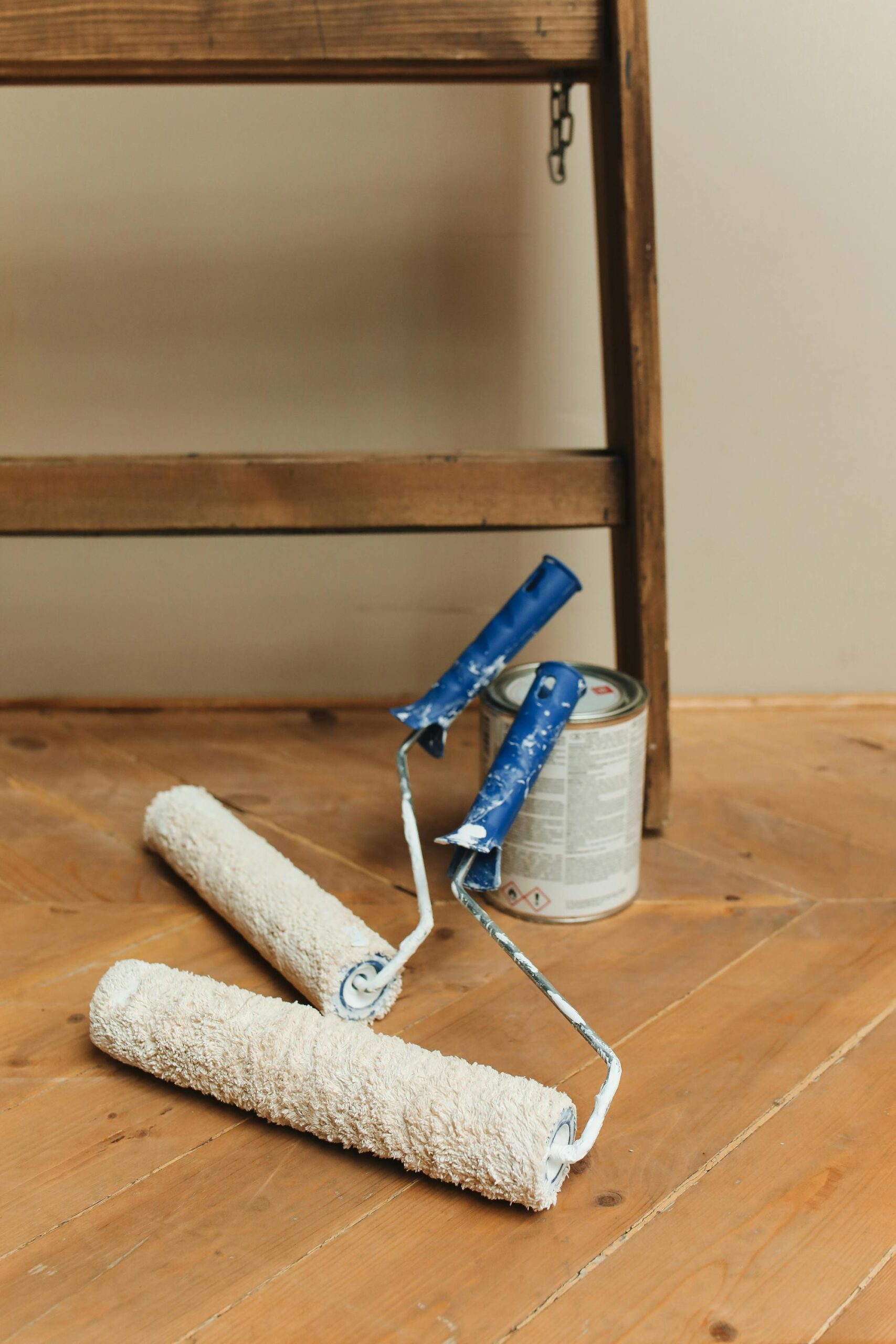 Paint rollers and can on a wooden floor, perfect for DIY home renovation projects.