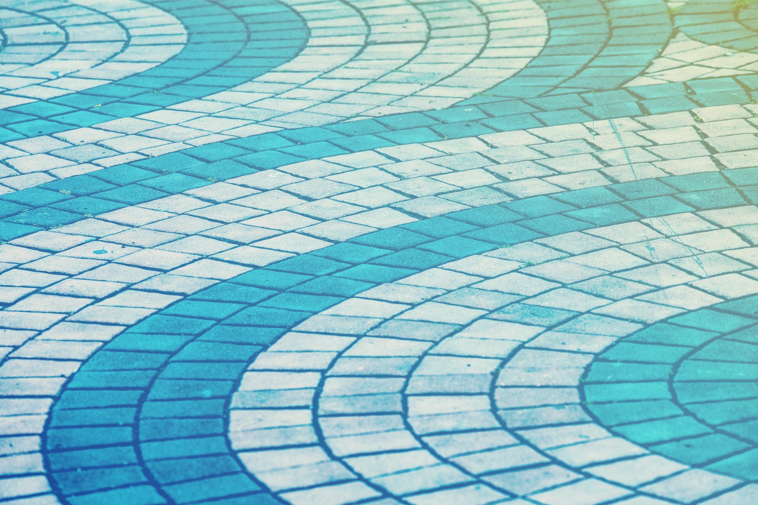 Curved blue and white paving tiles forming an abstract wave pattern on a walkway.